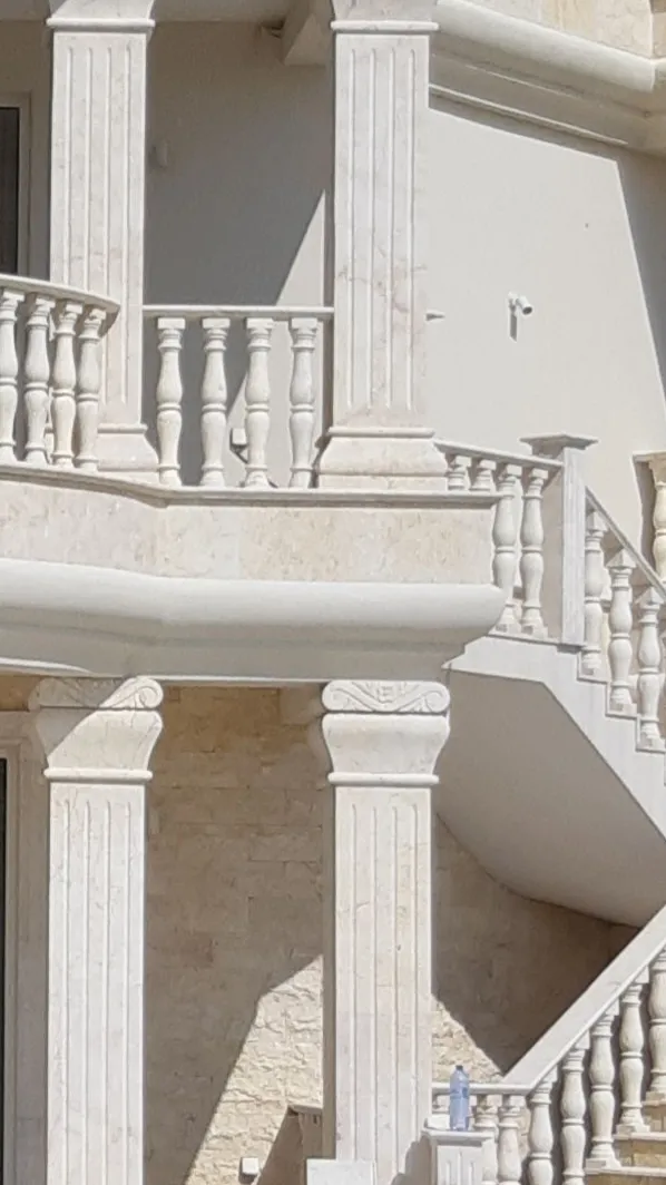 Stone balcony balustrade and columns on a rendered villa