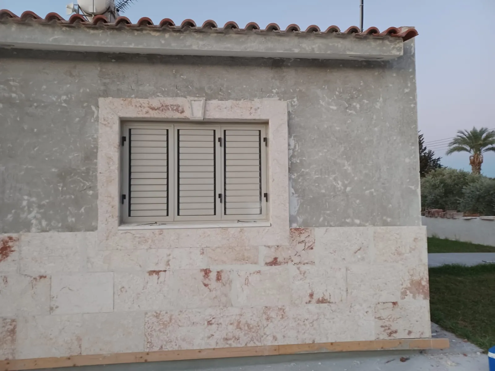 Stone cladding and carved surround framing a shuttered window