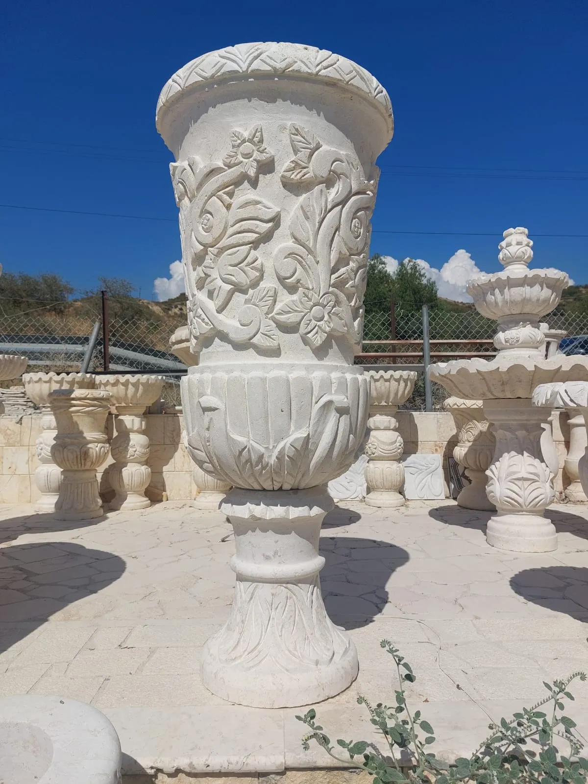 Tall carved stone urn with a floral relief