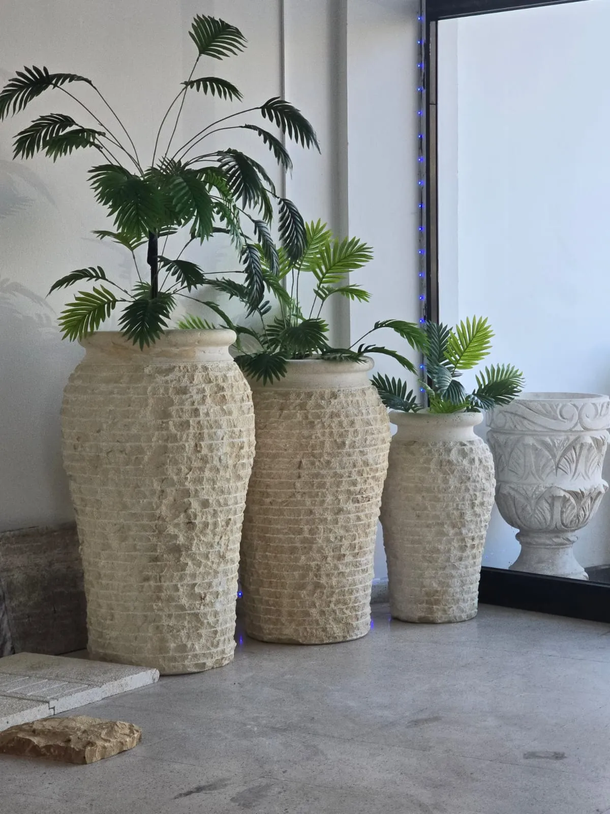 Stone planters displayed with palms in the showroom
